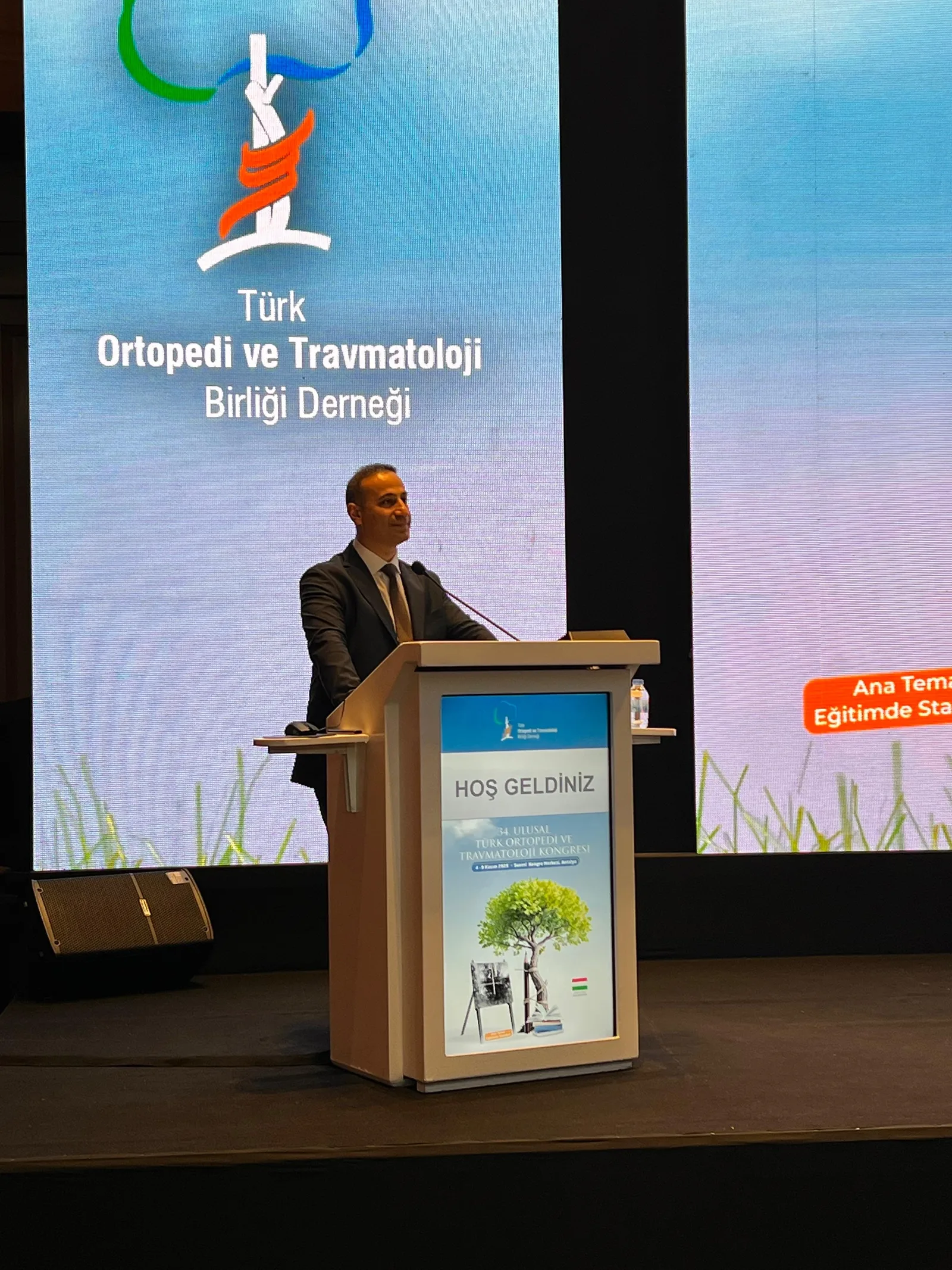 34. Ulusal Türk Ortopedi ve Travmatoloji Kongresi’nde kürsüde konuşurken; arkadaki ekranda TOTBİD amblemi.