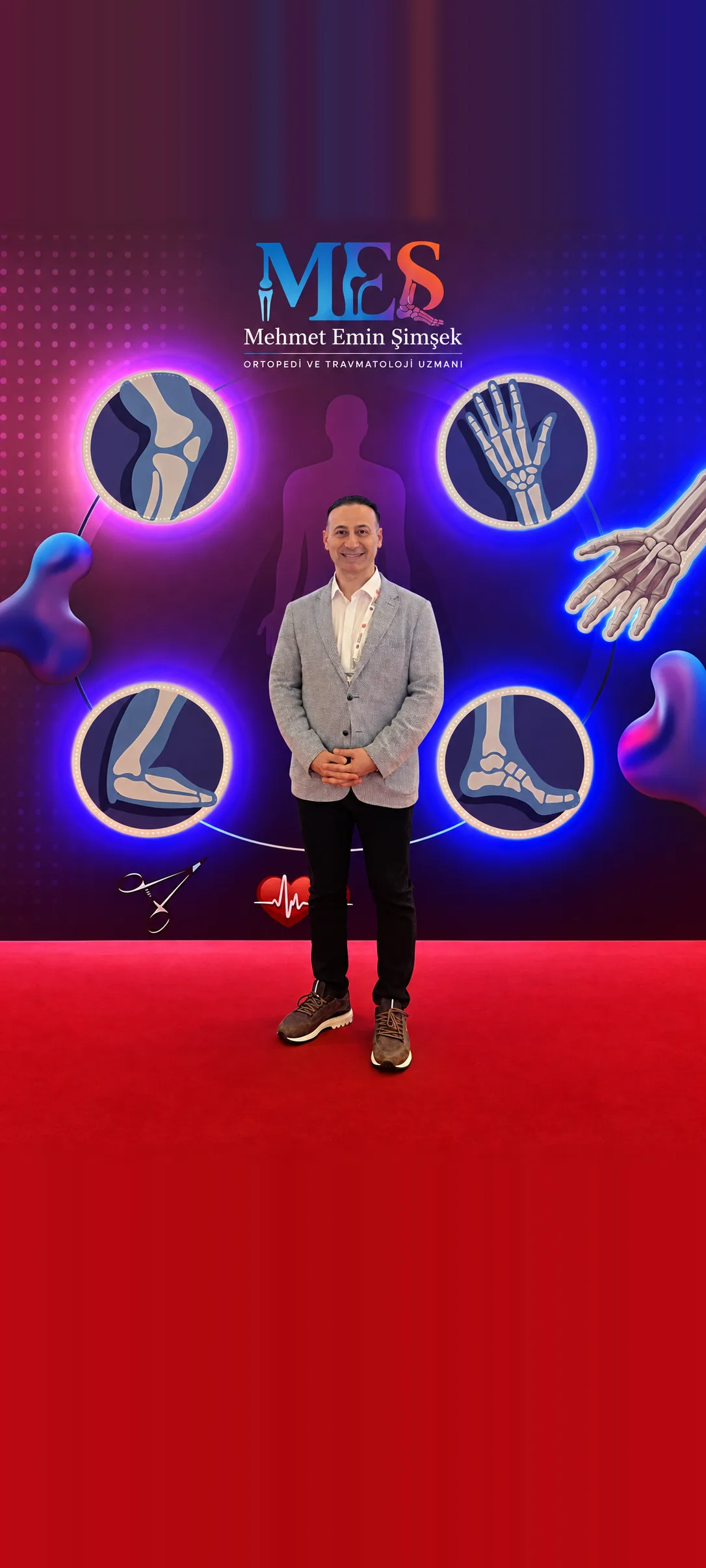 Prof. Dr. Mehmet Emin Şimşek, MEŞ logolu ortopedi fon panosunun önünde tam boy