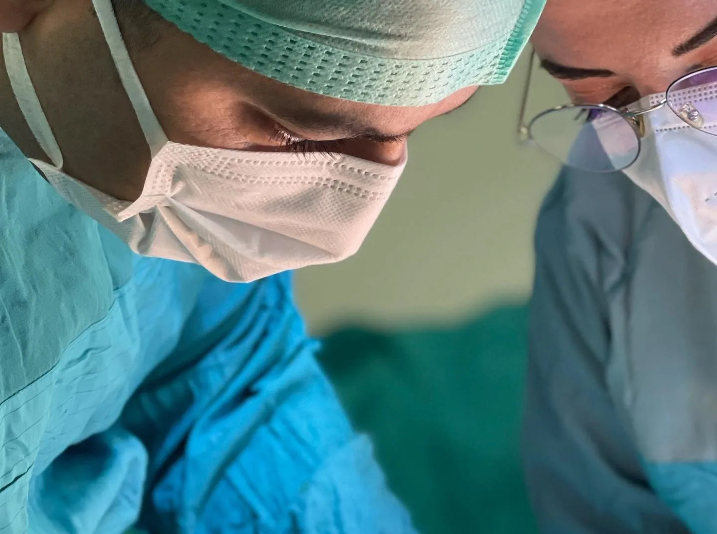 Maskeli iki ortopedi cerrahı ayak cerrahisi sırasında ameliyat sahasına odaklanmış.